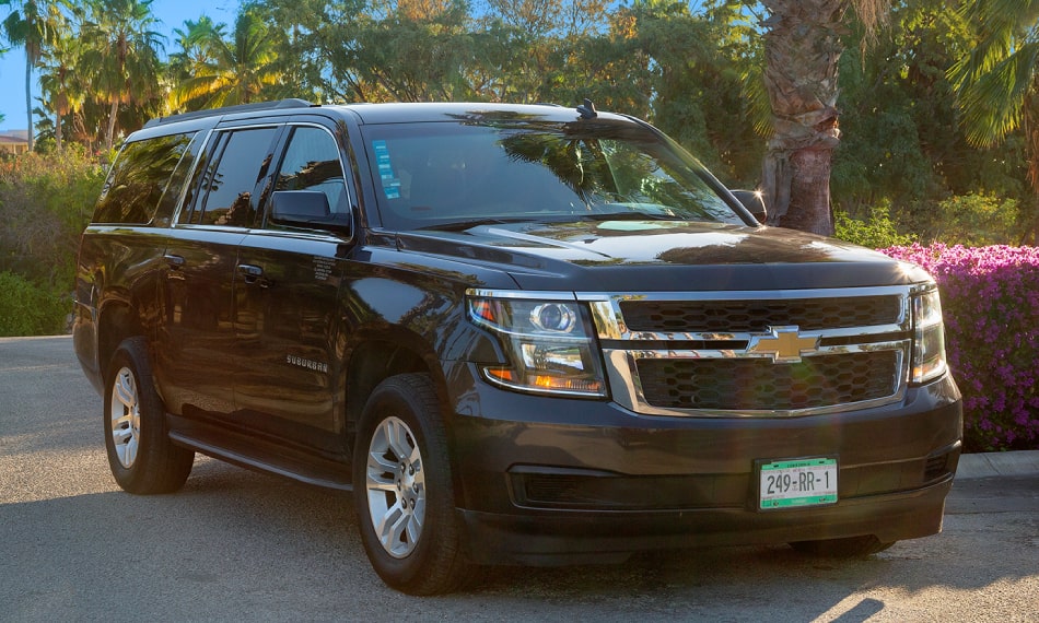 Black Chevrolet Suburban shown by Cabo Transfers in a palm-lined setting